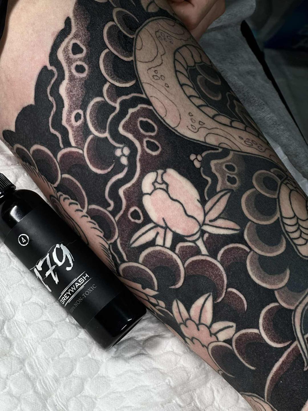 Chai số 4 set mực xăm Nhật cổ 179INK Grey Wash đặt cạnh bài xăm tay hoa mẫu đơn đen xám