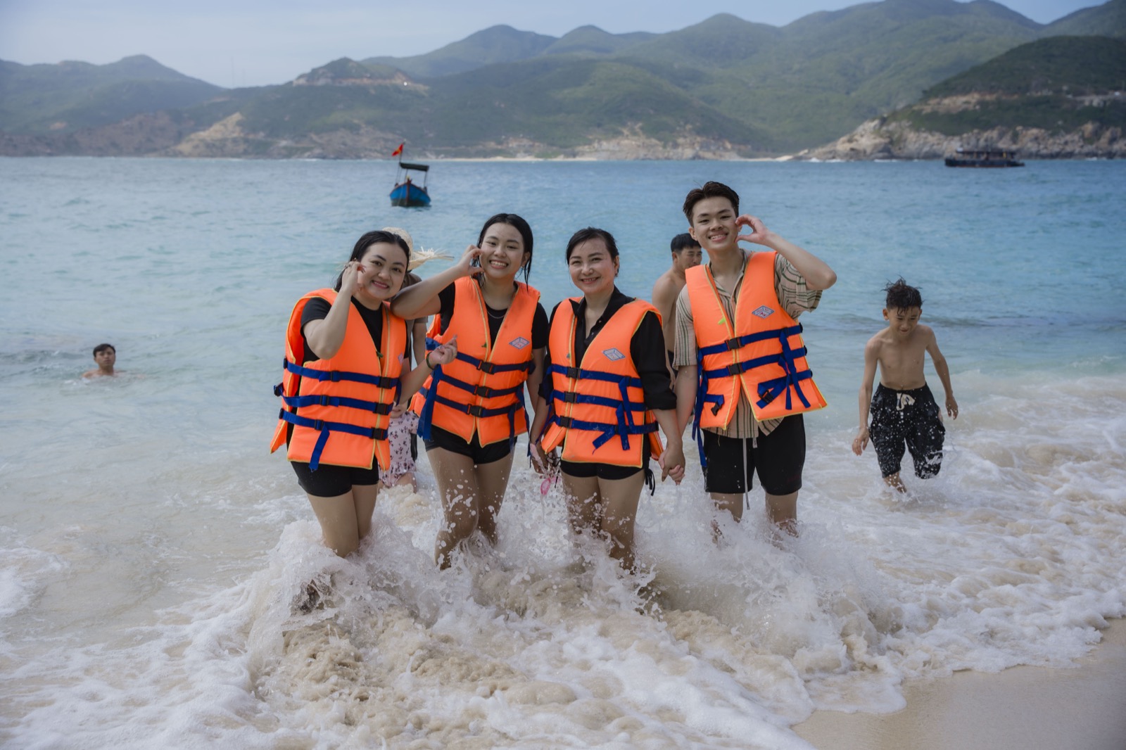 Trần Thị Thu Thảo cùng người thân đi biển, mặc áo phao cam bên mép sóng